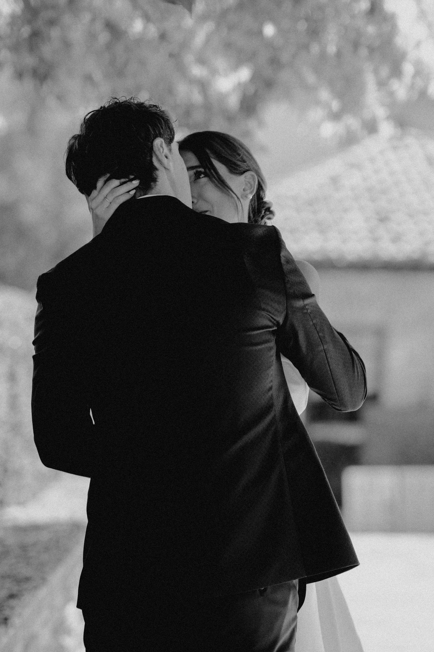 Black and white intimate portrait of newlyweds embracing during their wedding ceremony.