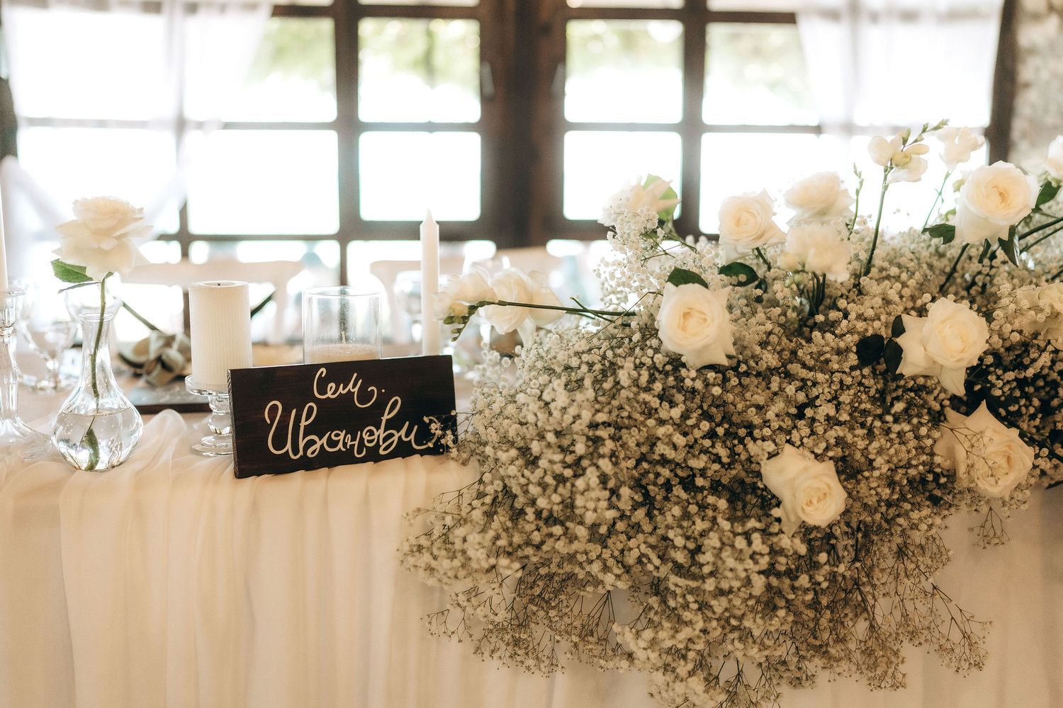Elegant white floral arrangements with baby's breath decorating a reception venue's windows.