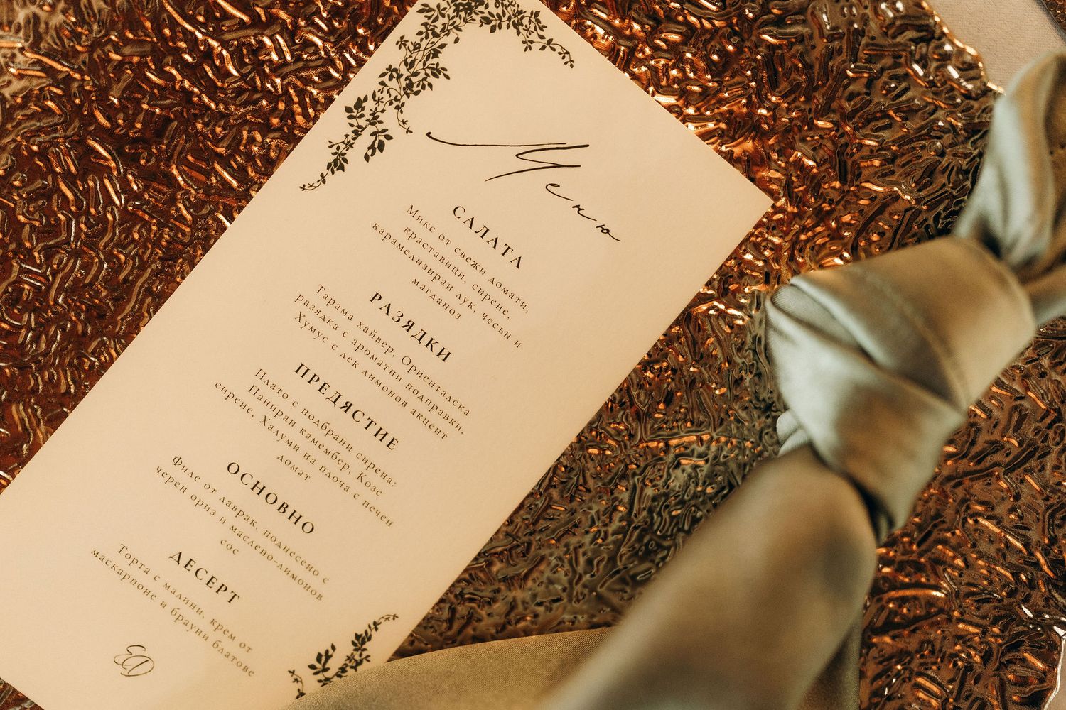 Wedding menu cards with elegant calligraphy displayed on textured copper placemats.