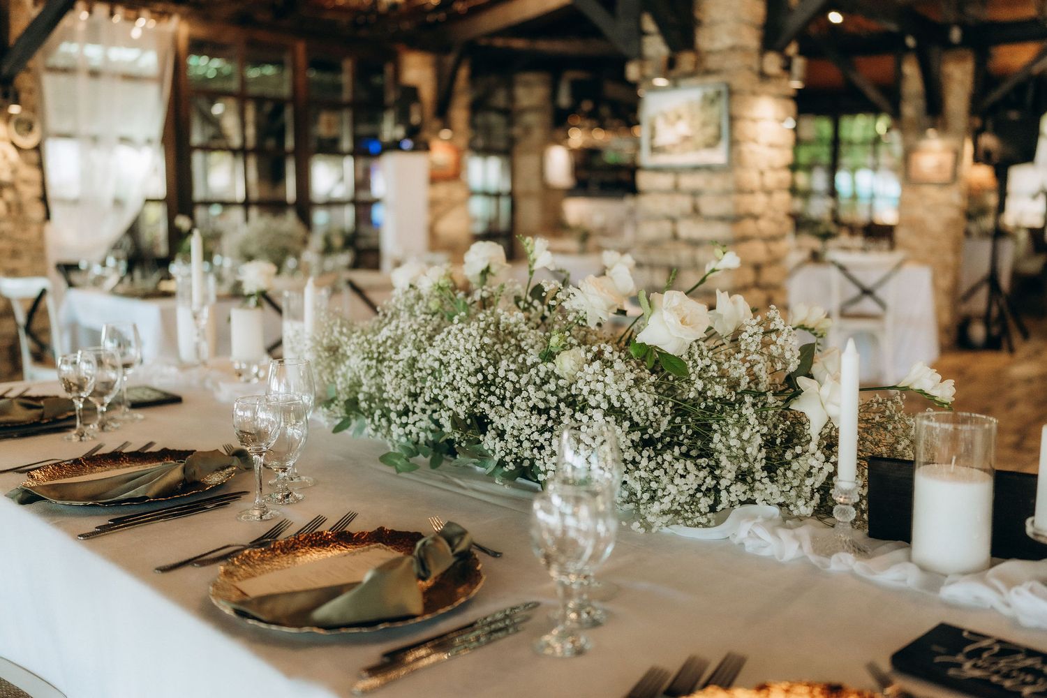 Rustic wedding reception tables set with elegant place settings and floral centerpieces.