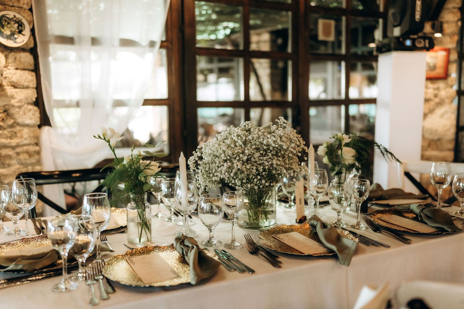 Stone-walled reception venue with elegant table settings and natural lighting.