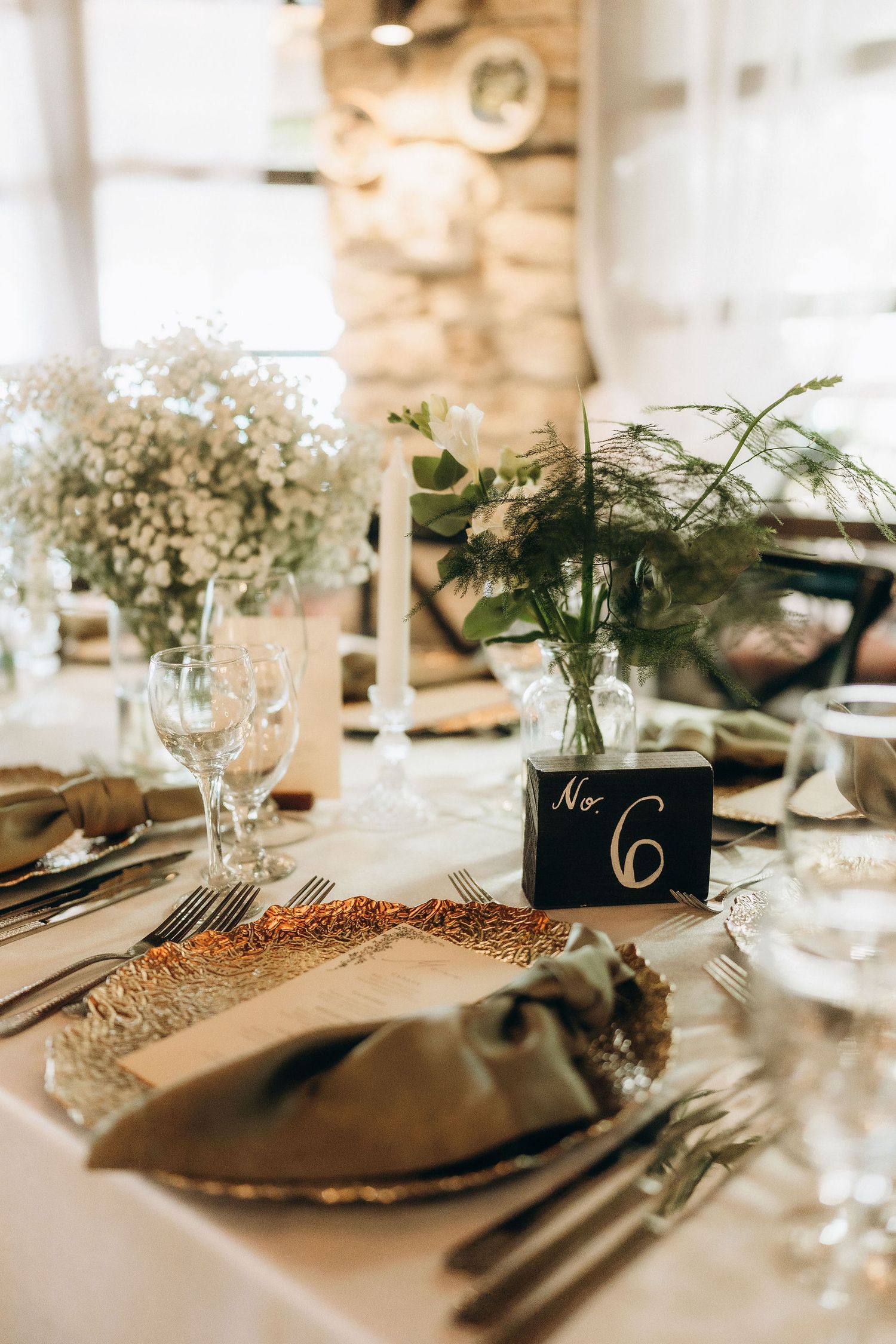 Elegant table settings with black table numbers and baby's breath centerpieces.