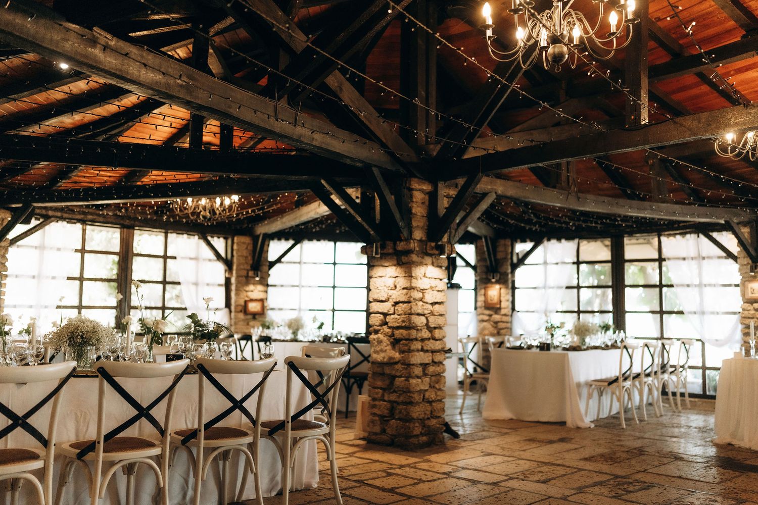 Rustic barn wedding venue with exposed wooden beams and chandeliers.