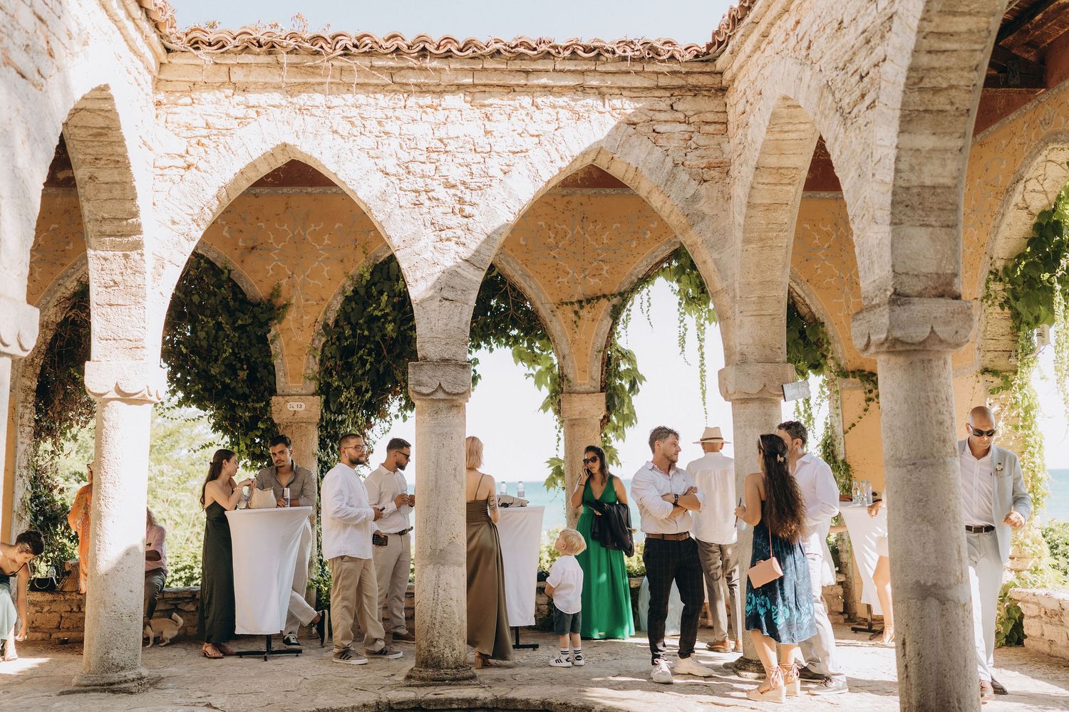 Stone archway courtyard with Mediterranean architecture filled with wedding guests.