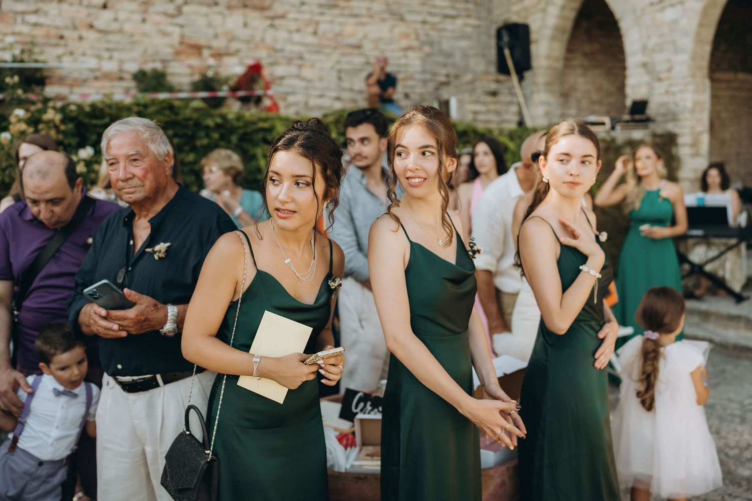 Wedding guests in elegant green dresses gathered at an outdoor celebration.