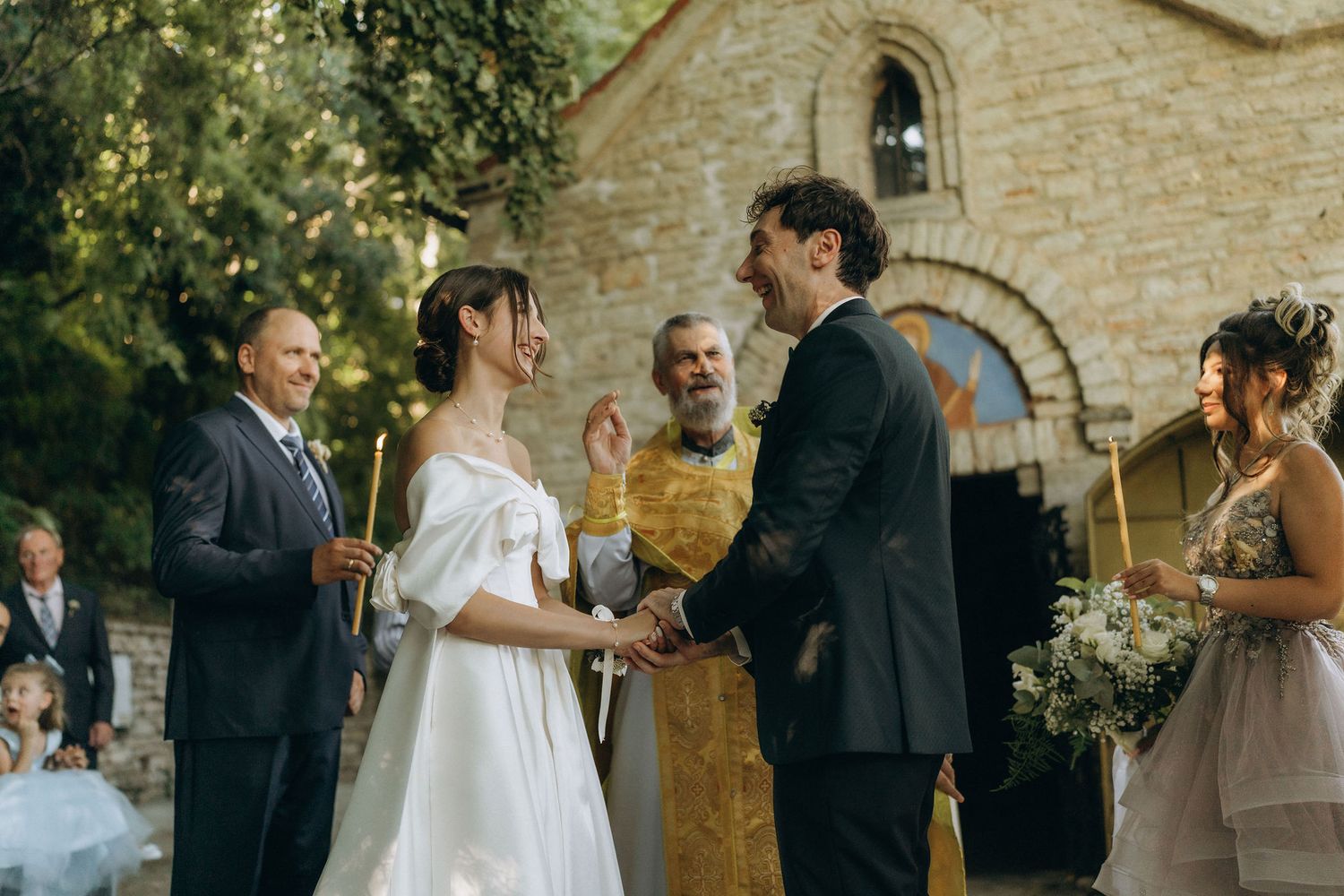Traditional stone chapel facade with religious iconography during wedding ceremony.