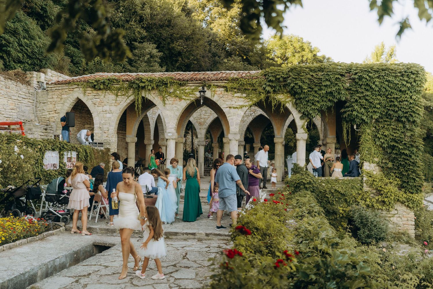 Arched stone walkway covered in lush green ivy and flowers creates a romantic garden setting.
