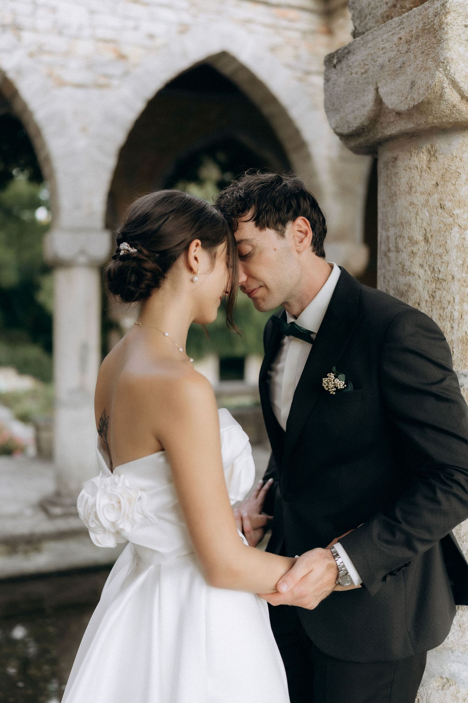 A romantic moment between newlyweds under stone archways at an elegant venue.