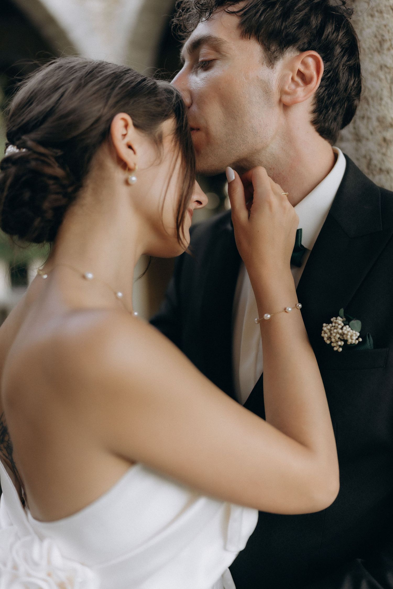 Intimate wedding couple sharing a tender moment under stone architecture.