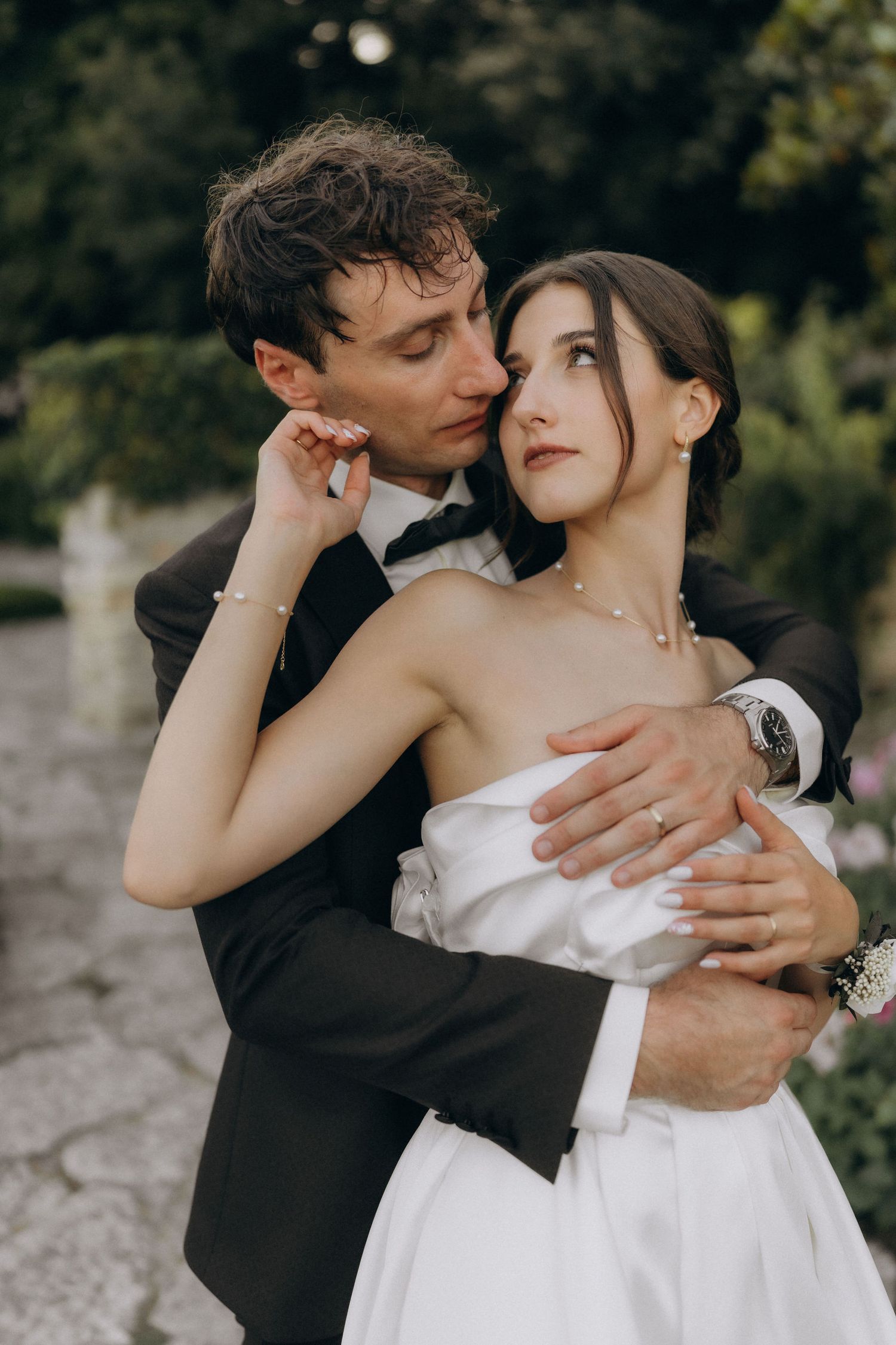 Intimate wedding portrait captured on stone path with romantic garden backdrop.