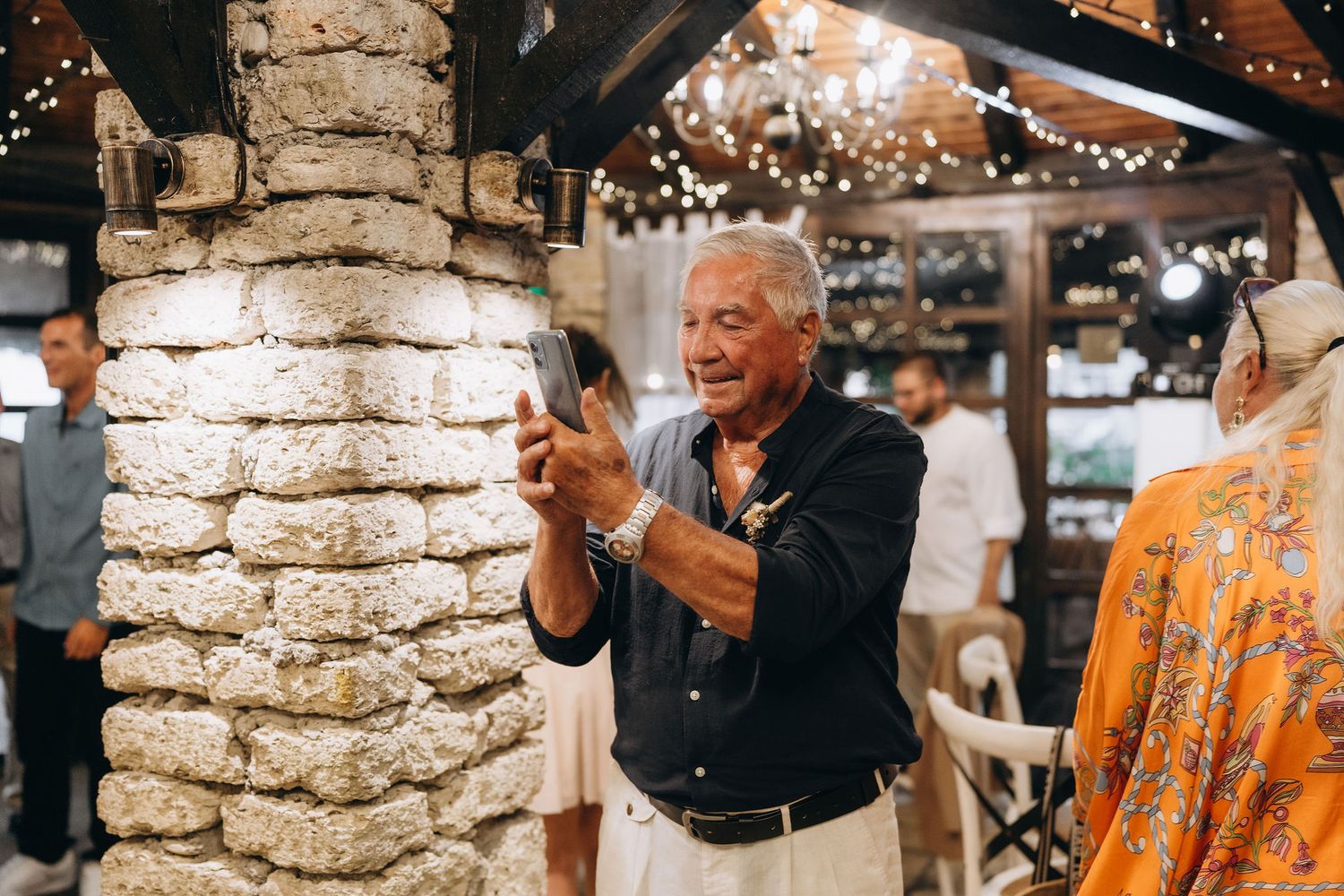 Guest enjoying festivities at an indoor reception venue with stone columns and string lights.