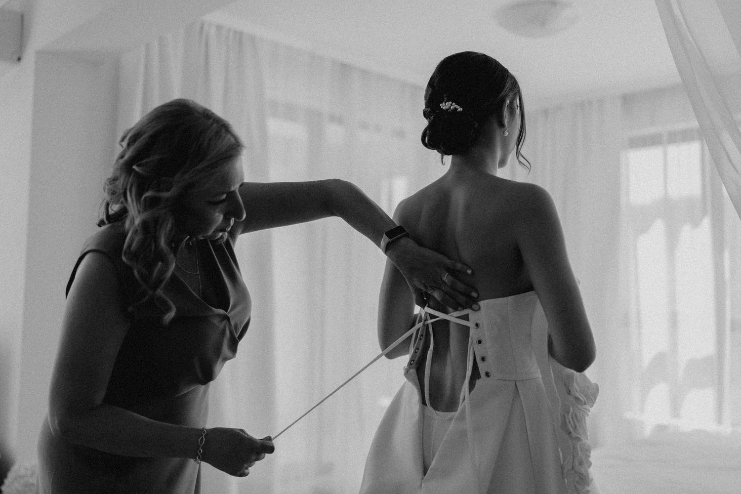 Black and white photos showing wedding dress preparation in a sunlit room.