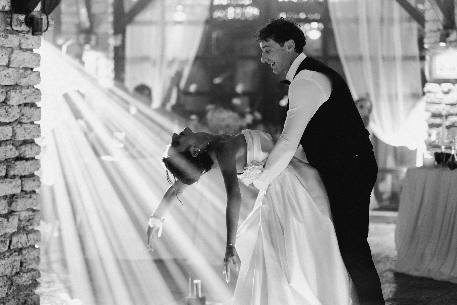 A romantic wedding dip kiss captured in a series of black and white photos with soft lighting.