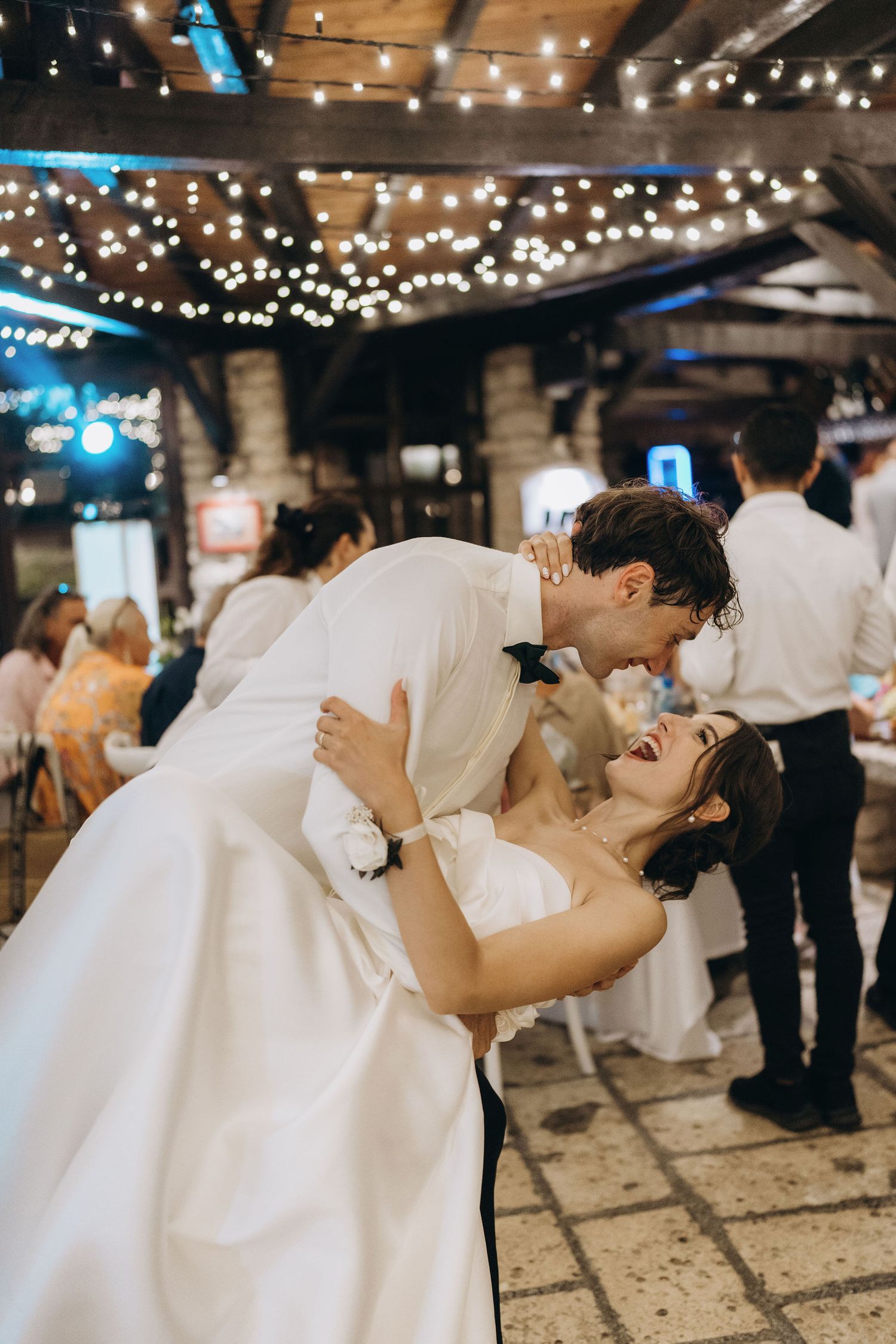 Newlyweds share an intimate dance under twinkling string lights at their wedding reception.