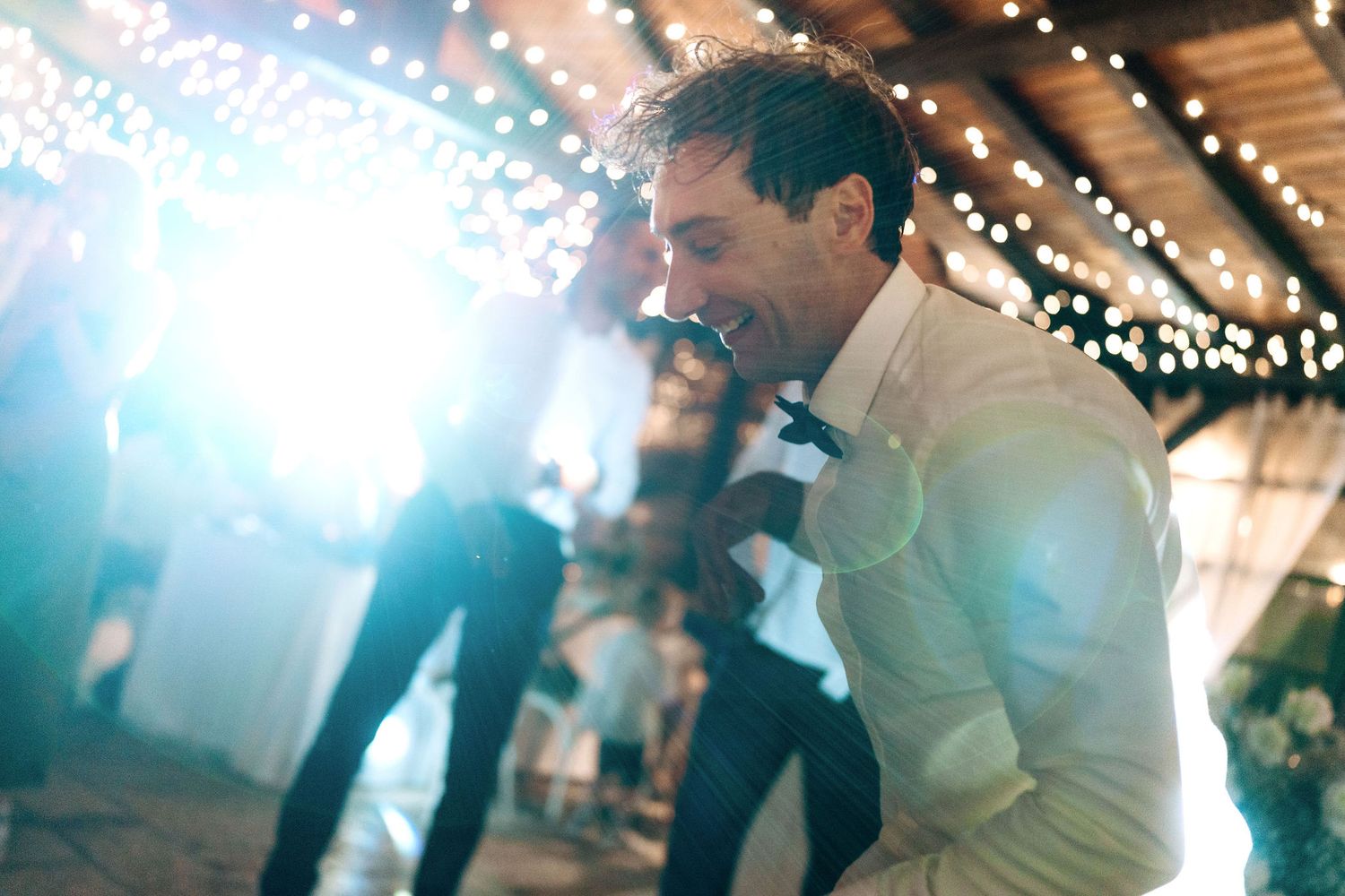 Wedding reception dance floor moment captured under glowing string lights.