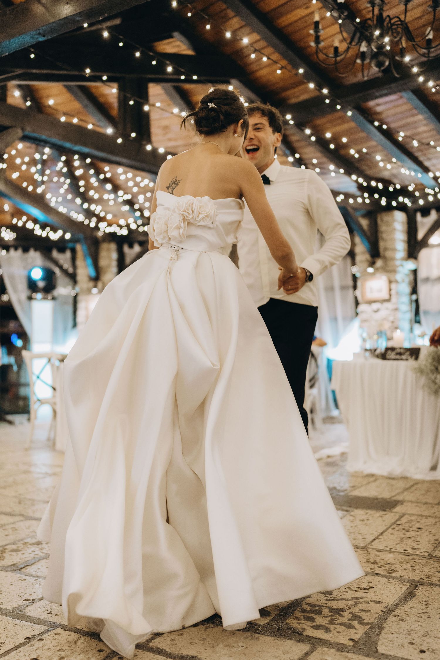Bride in flowing white ballgown twirls on dance floor under sparkling venue lights.