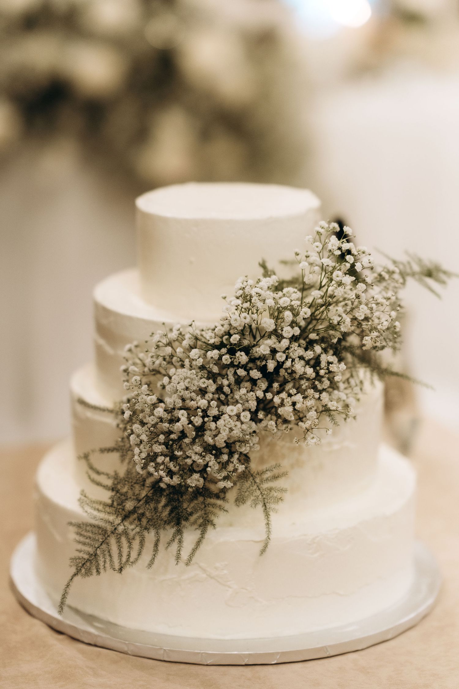 Elegant white wedding cake decorated with delicate baby's breath flowers and greenery.