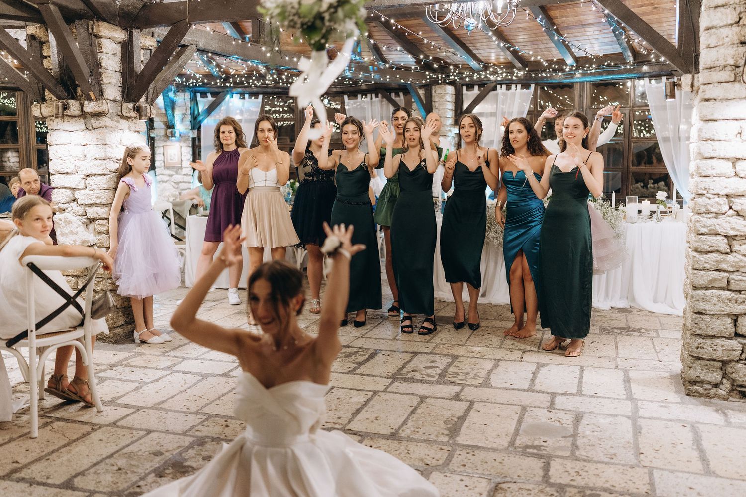 Wedding guests cheering and celebrating in an elegant stone-walled venue.