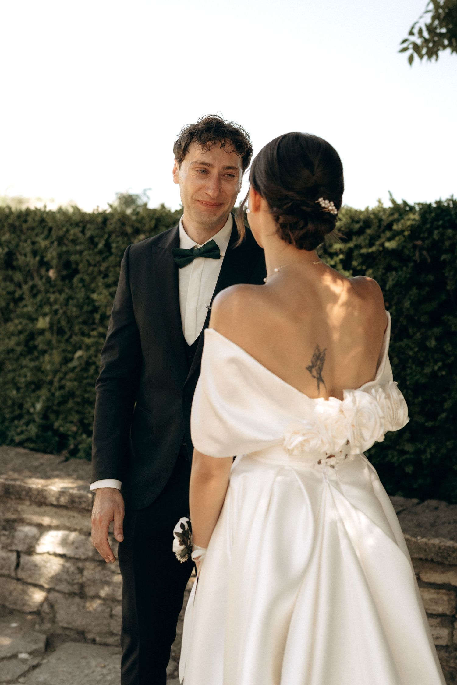 A couple shares an intimate moment during their wedding ceremony against a stone wall backdrop.