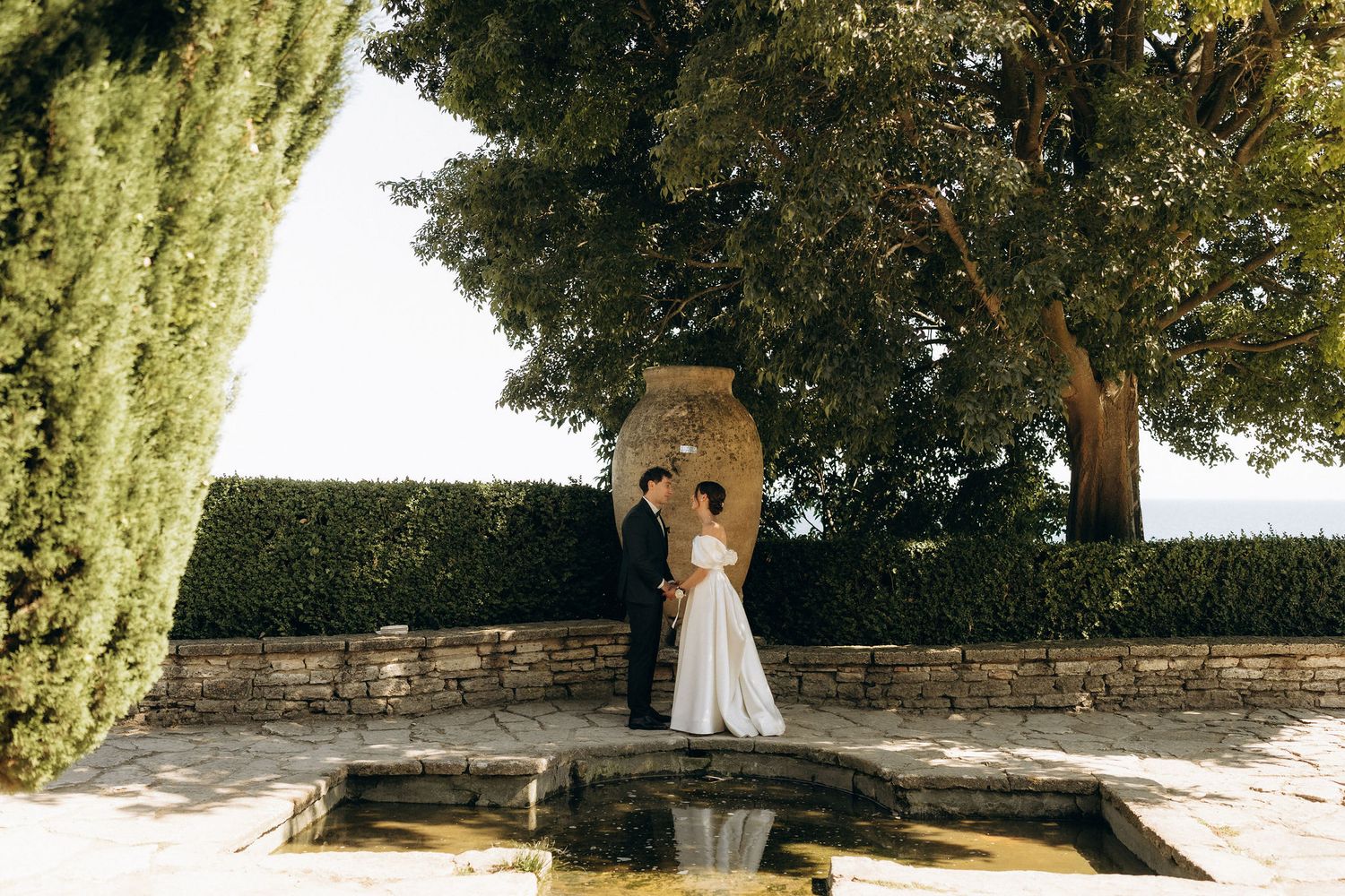 Scenic garden wedding venue with stone walls and lush trees creating a natural backdrop.