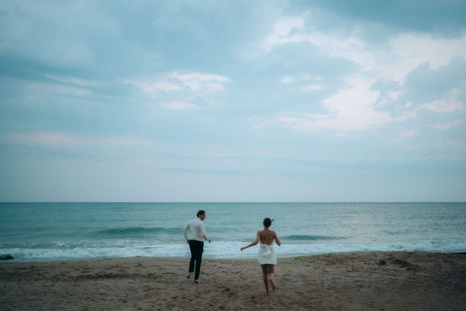 Couple enjoying peaceful moment by ocean under cloudy sky.