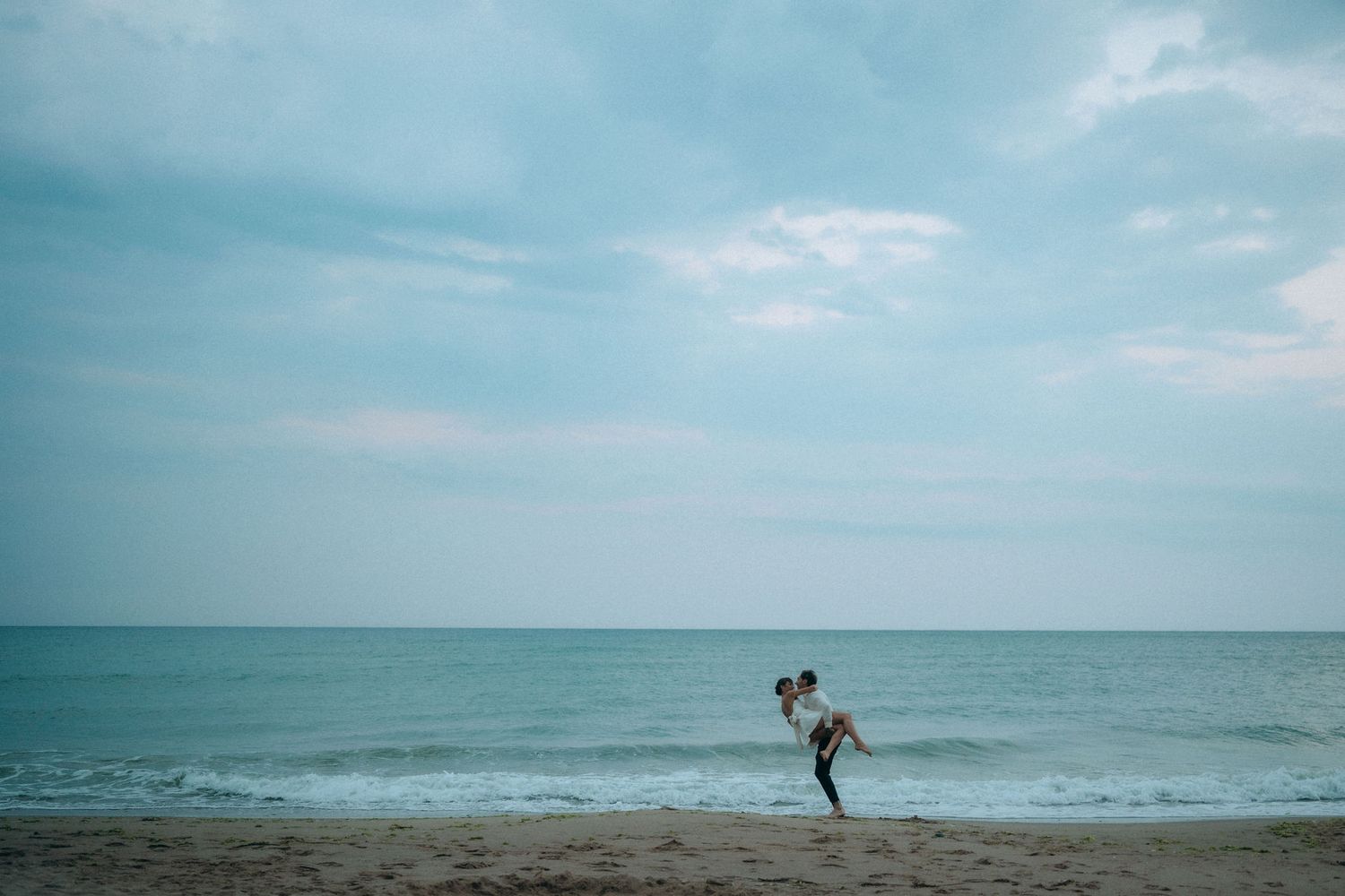 Serene oceanfront scene with turquoise waters and cloudy horizon.