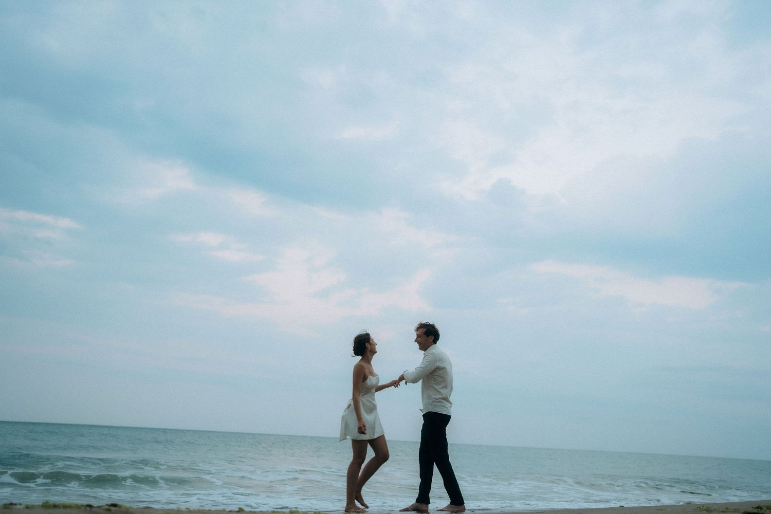 Couple sharing romantic moment on beach during engagement photoshoot.