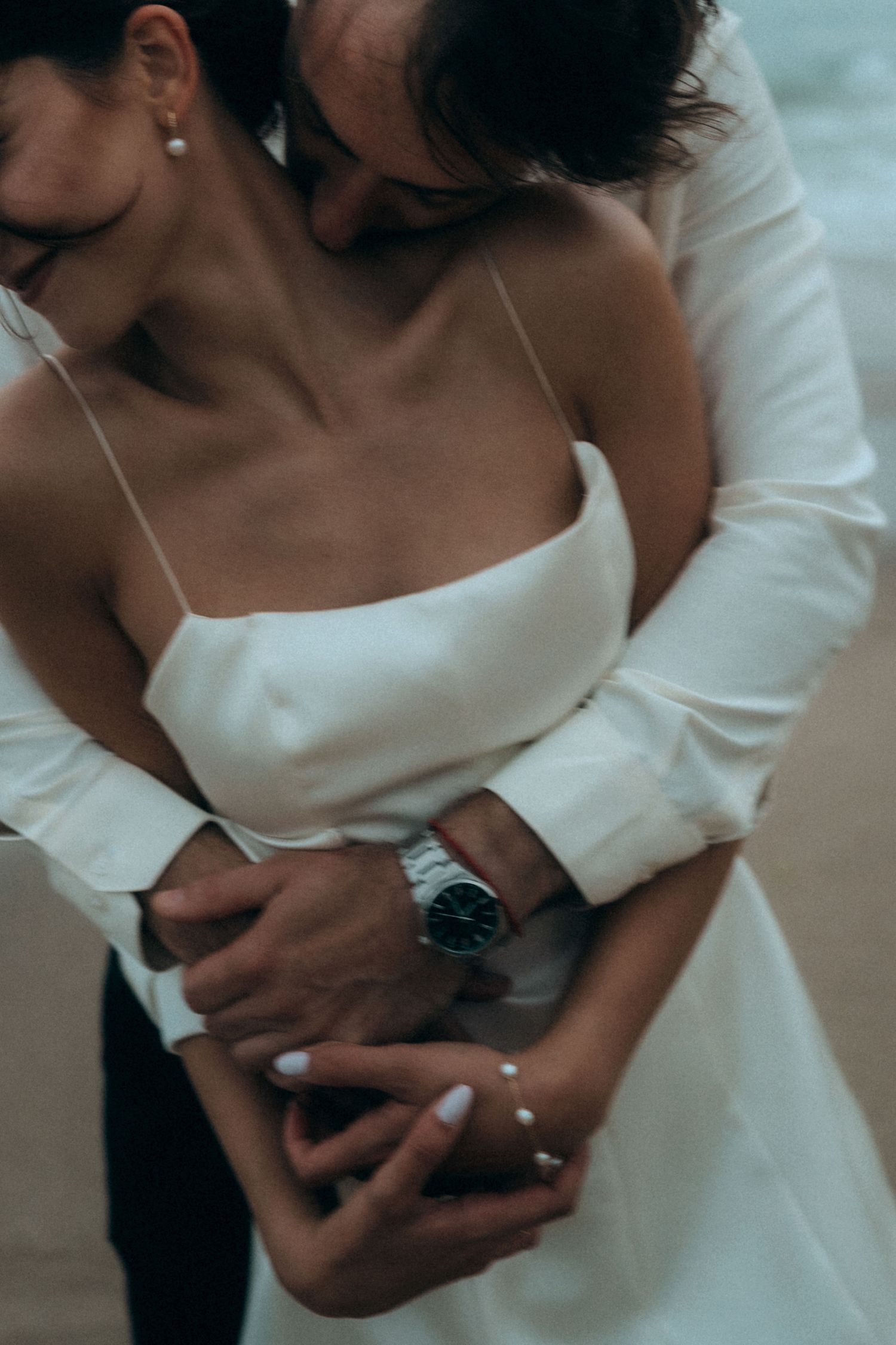 Close up of couple in wedding attire sharing an intimate moment on the beach.