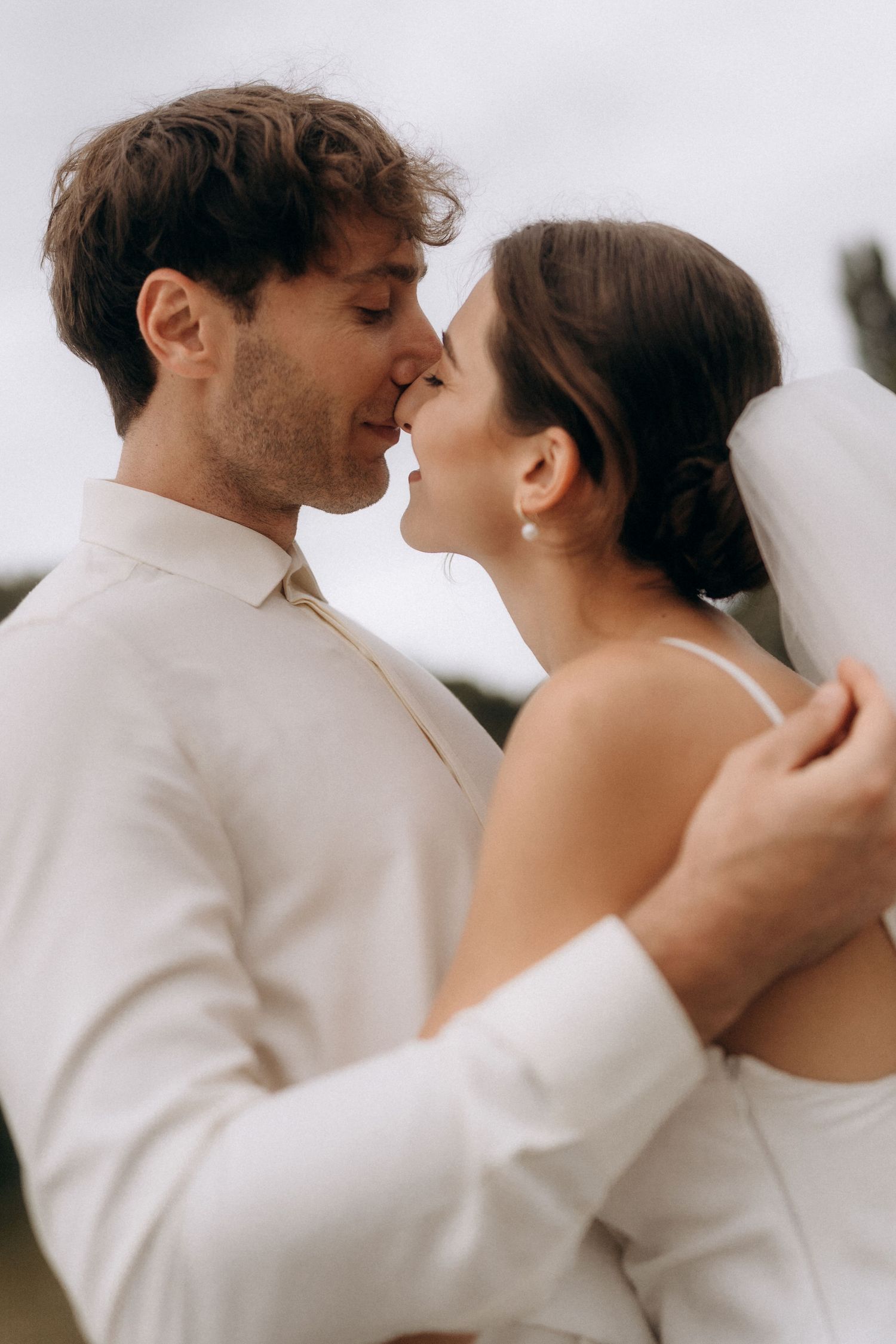Artistic wedding portraits showing tender moments between newlyweds in white attire.