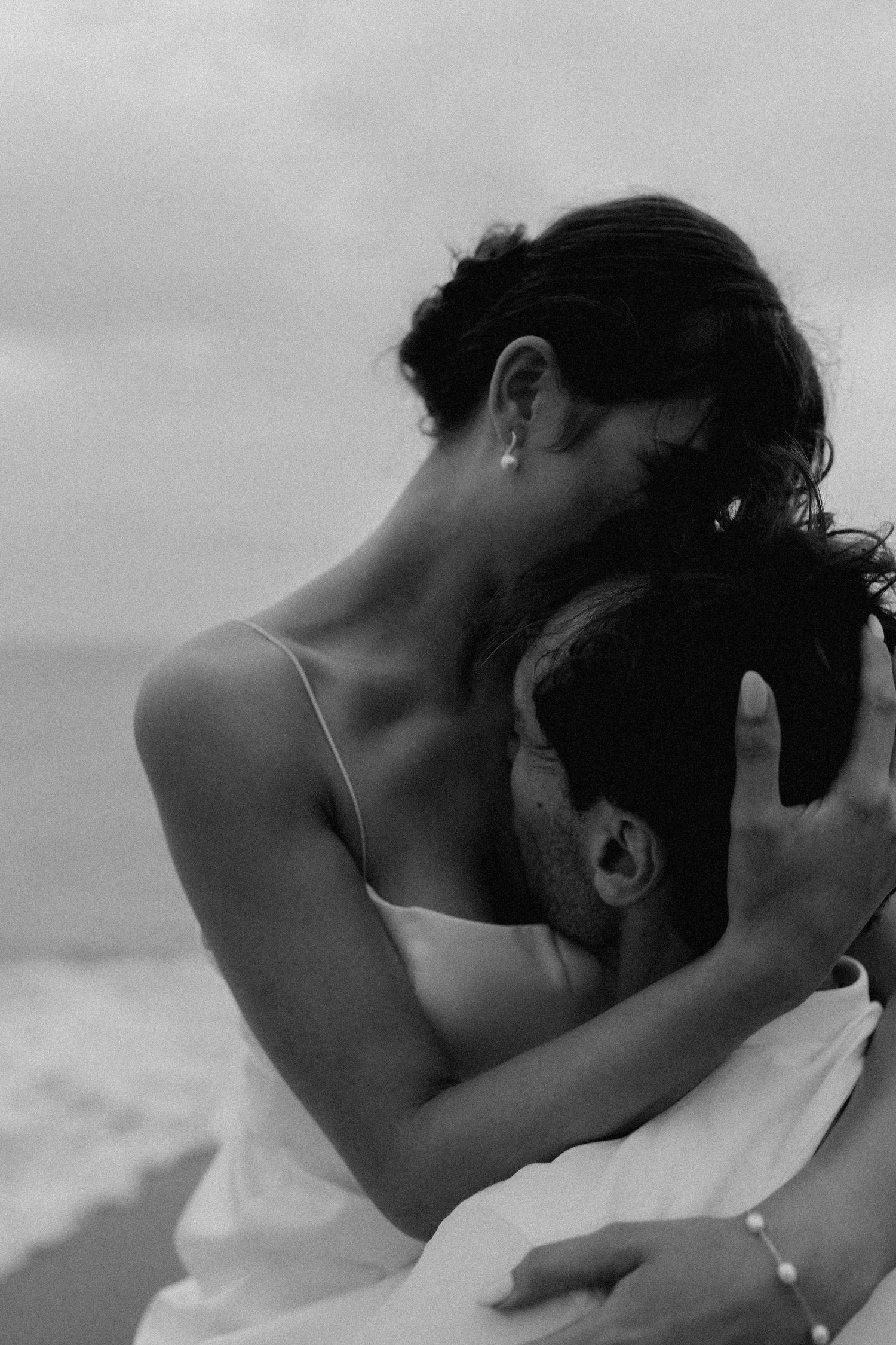 Black and white close-up of romantic couple sharing tender moment by the ocean.