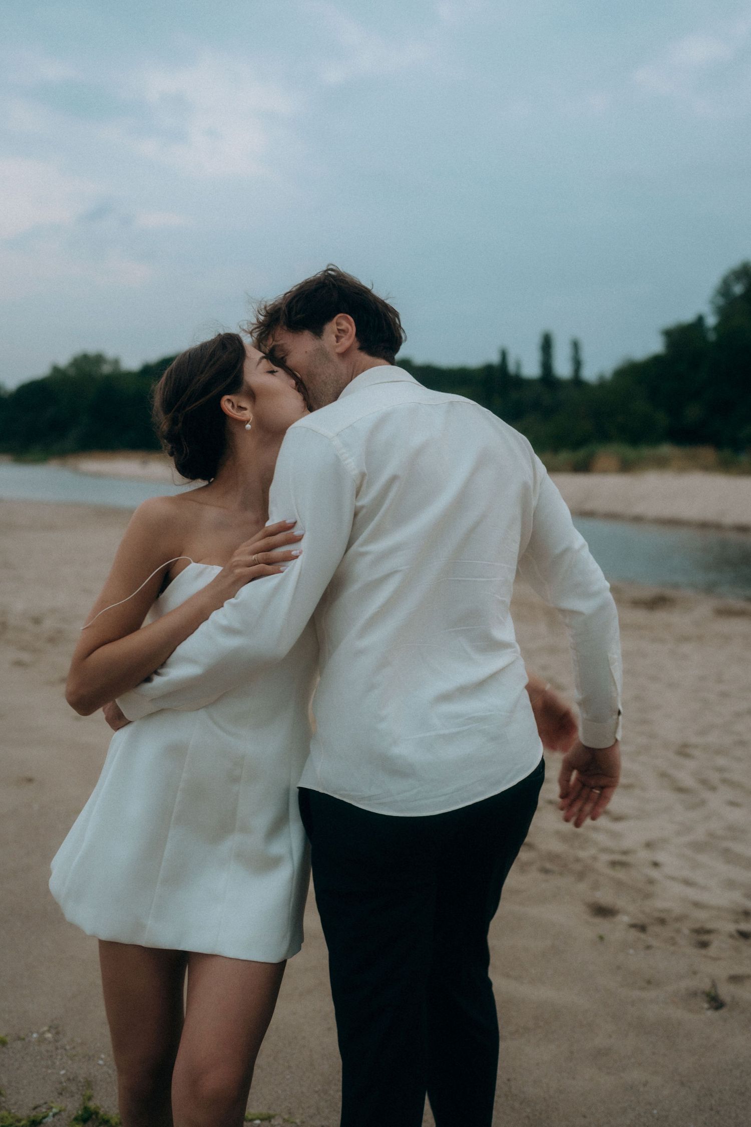 A romantic embrace between a couple on a sandy beach during golden hour.