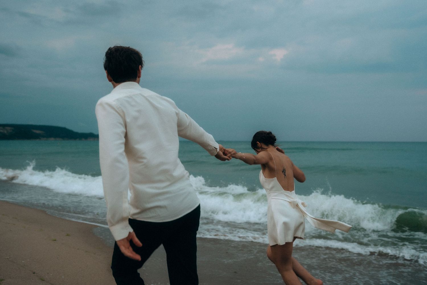 A couple playing and dancing together by the ocean waves.