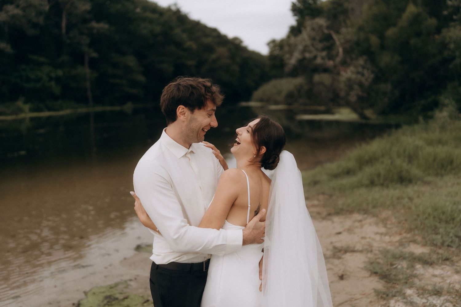 Wedding couple sharing intimate moments by the water's edge.