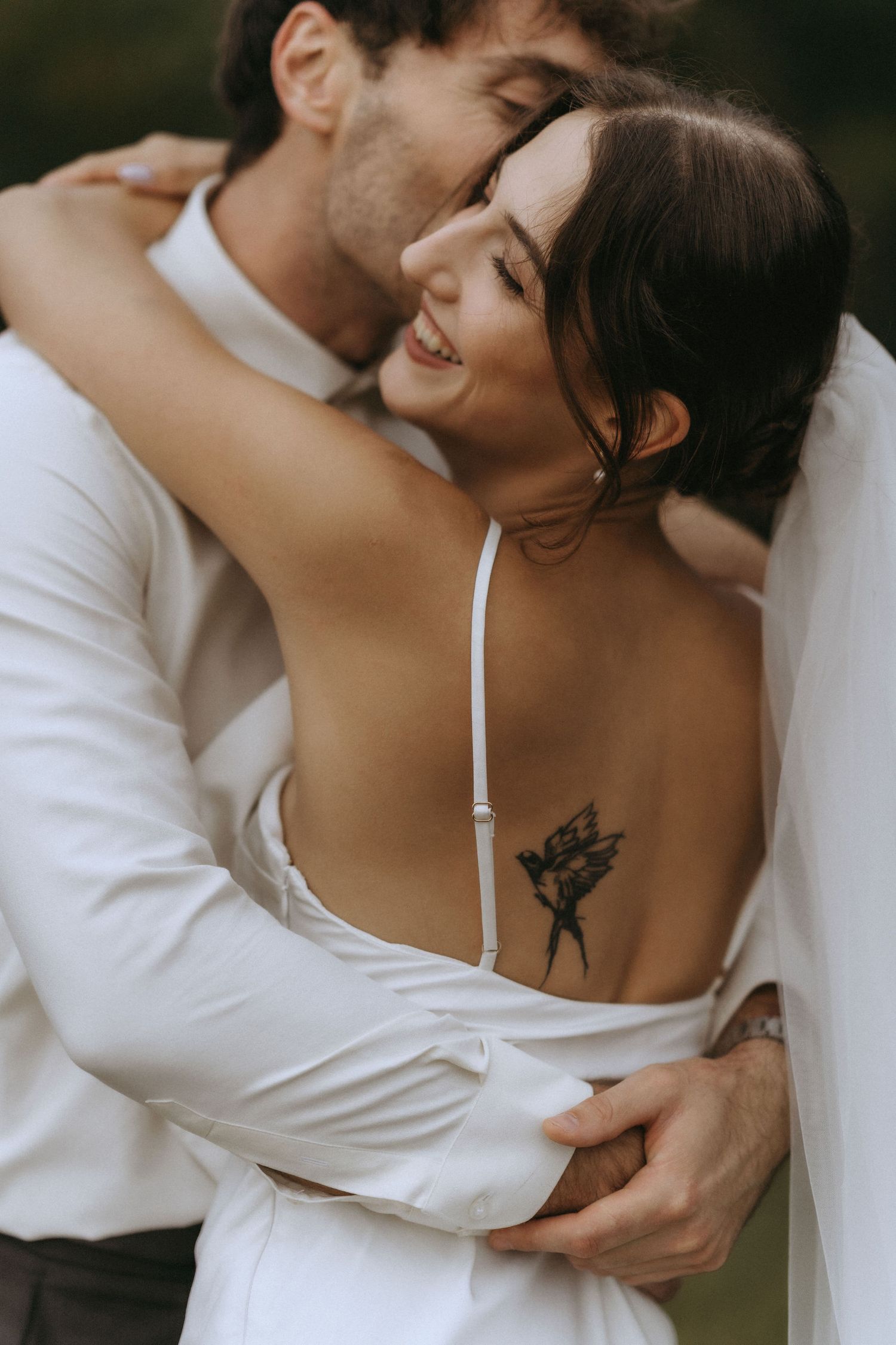 Intimate couple shares tender moments in white clothing against a natural backdrop.