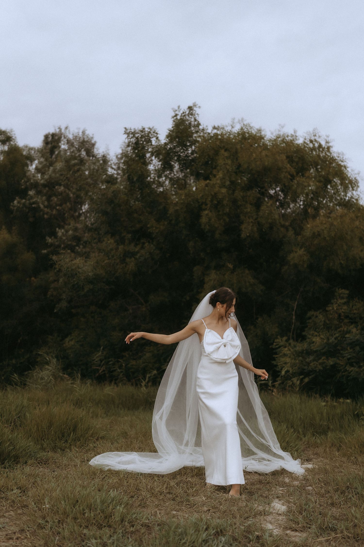 Ethereal bridal portrait with flowing veil dancing in the wind against autumn foliage.