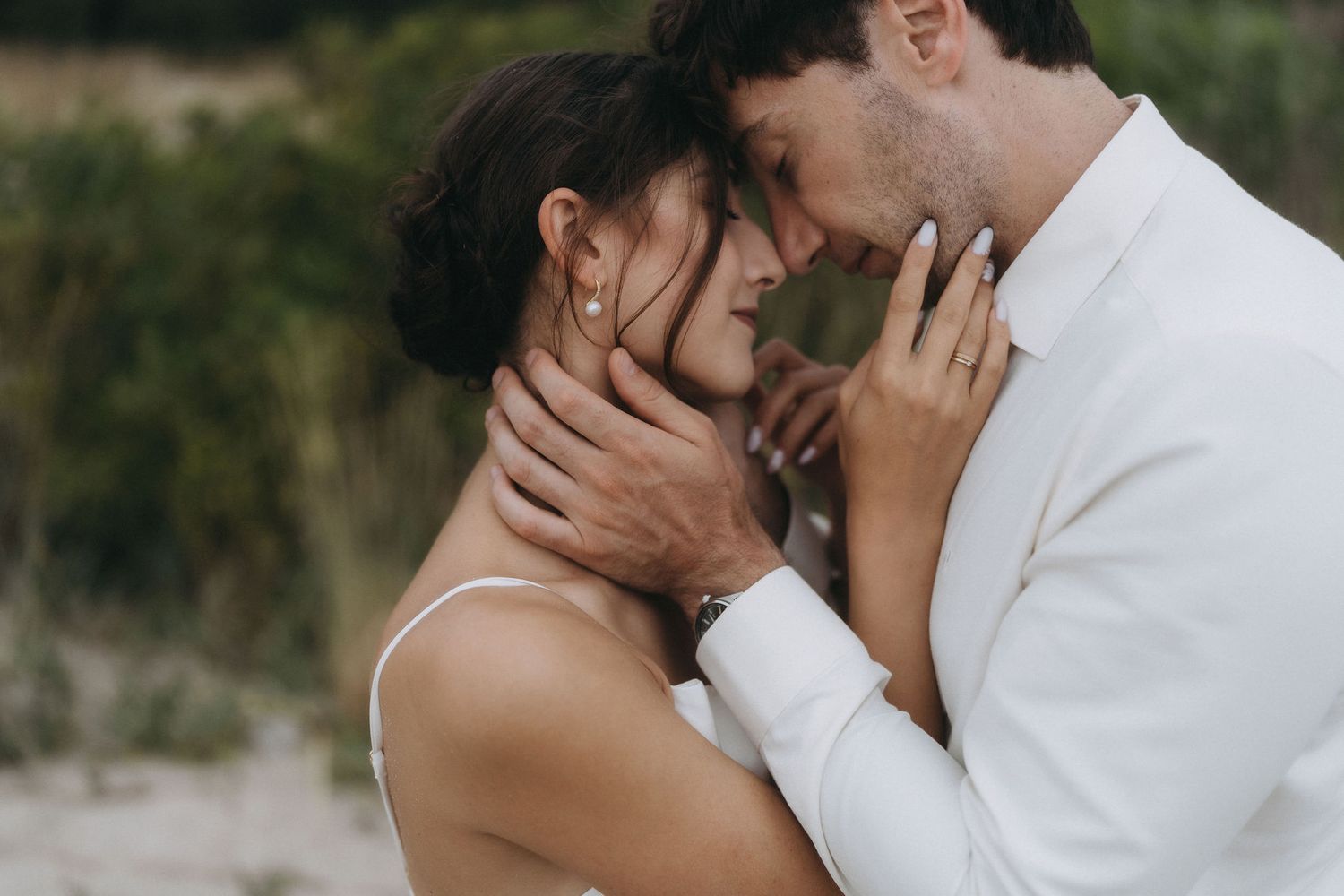 Intimate beach engagement photos with couple in white and dark attire.