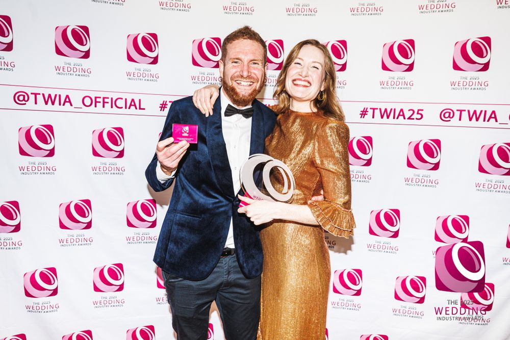 Award winners posing with trophy and box at the TWIA 2025 photo backdrop wall.