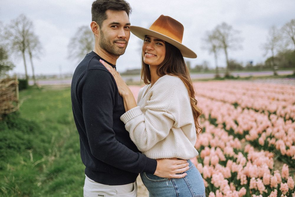 A romantic couple embraces in a field of pink tulips during a springtime photoshoot.