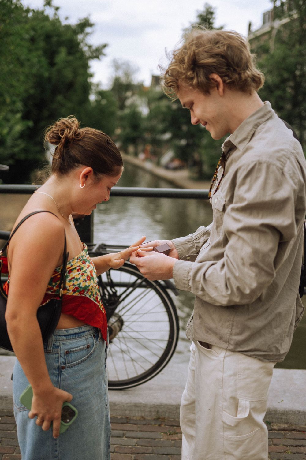 A couple interacts by a waterfront railing on an overcast day.