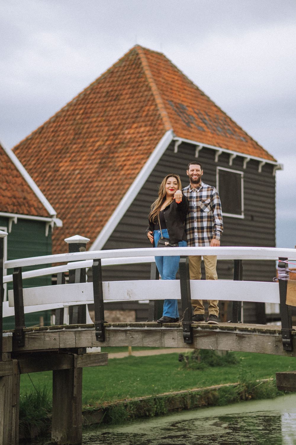 Traditional Dutch houses with orange tiled roofs stand along a waterfront.