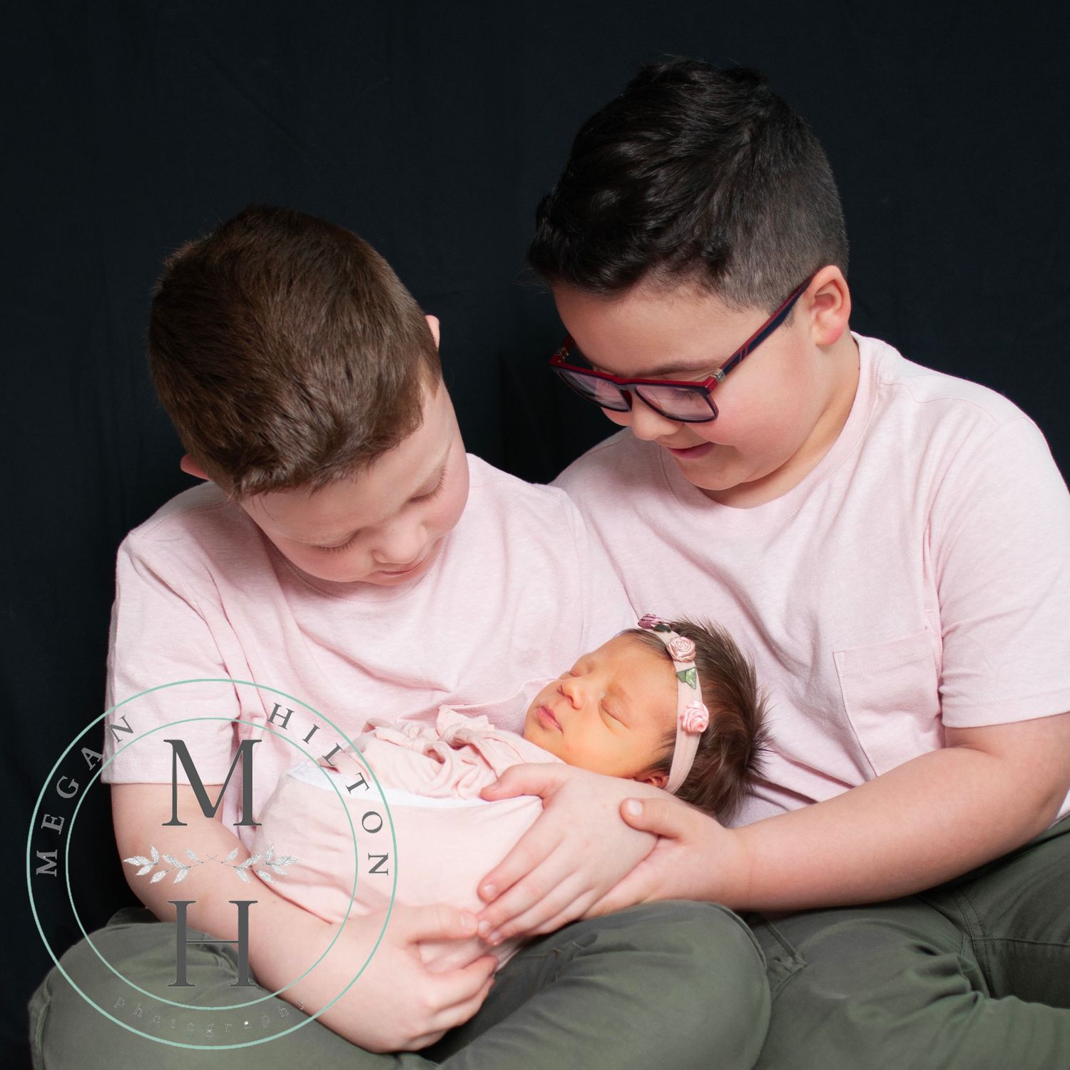 Older brothers holding newborn sister and looking at her candid photo