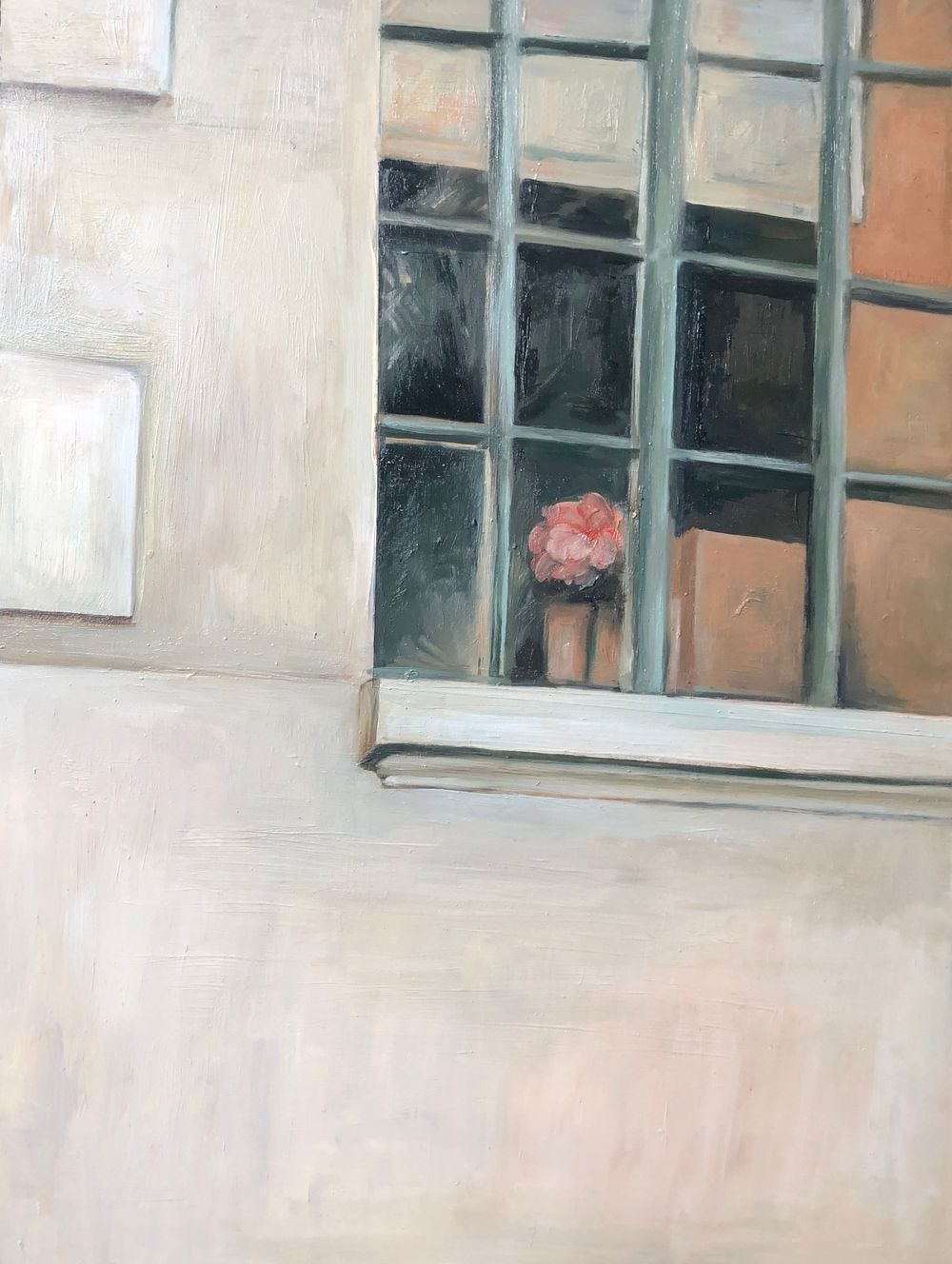 An industrial window with metal grid framing reveals a pink potted flower on the interior ledge against a beige wall.