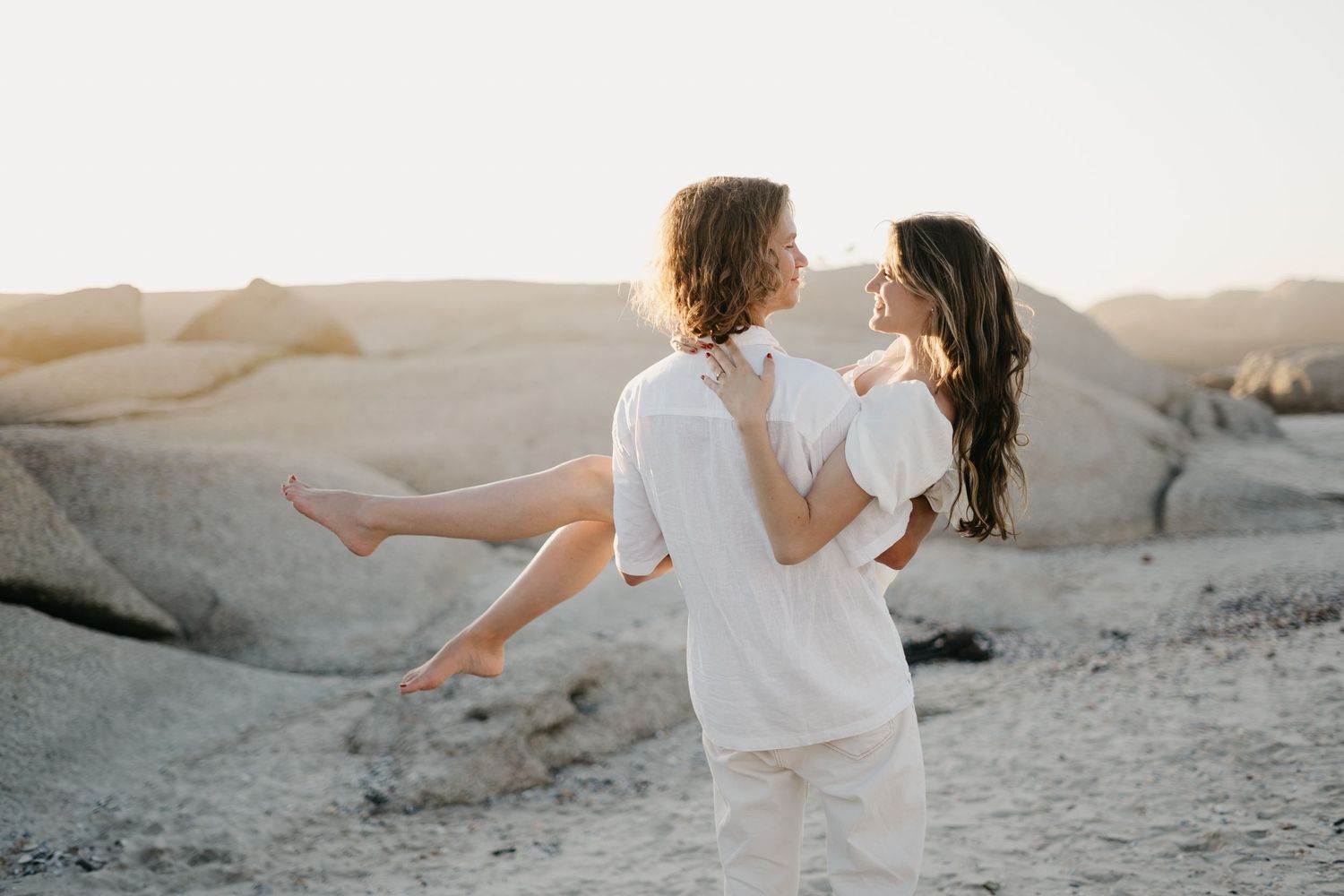 Couple in love surrounded by the beautiful western cape beach scenery with mountains and water in back at Clifton 4th Beach in South Africa