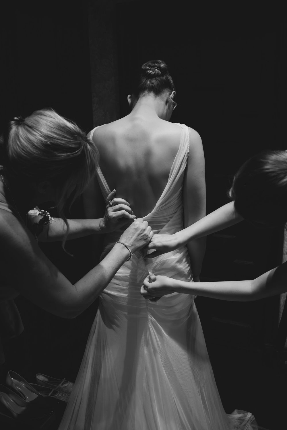 Black and white photos show final dress adjustments being made to a wedding gown before the ceremony.
