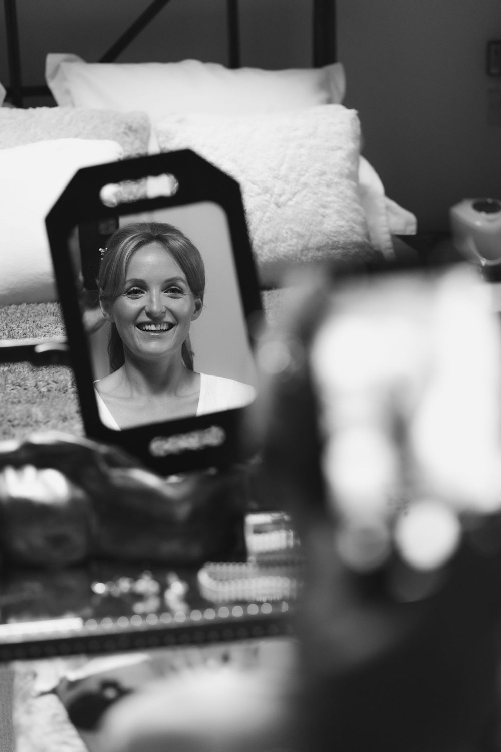 A series of black and white photographs showing candid smiling expressions through mirrors and reflective surfaces.