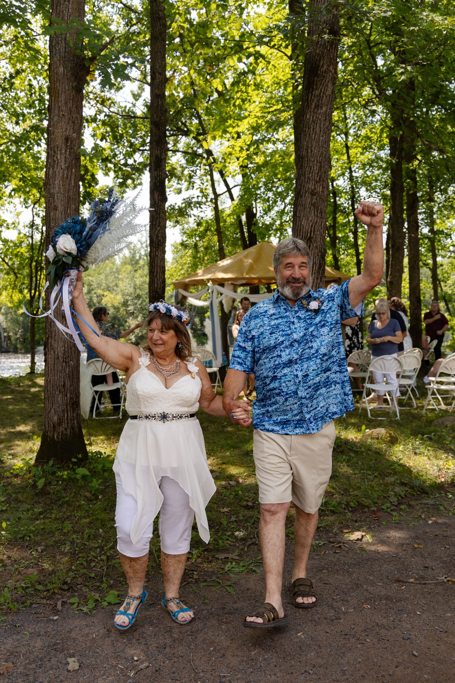 Newlyweds celebrating with joyful poses outdoors at woodland wedding ceremony.