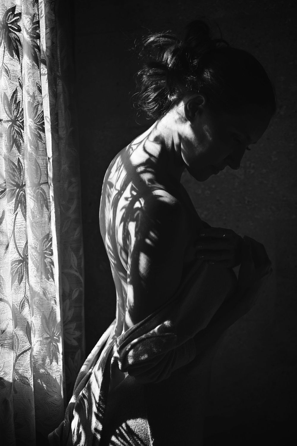 Moody black and white fine art portrait of a woman by the window