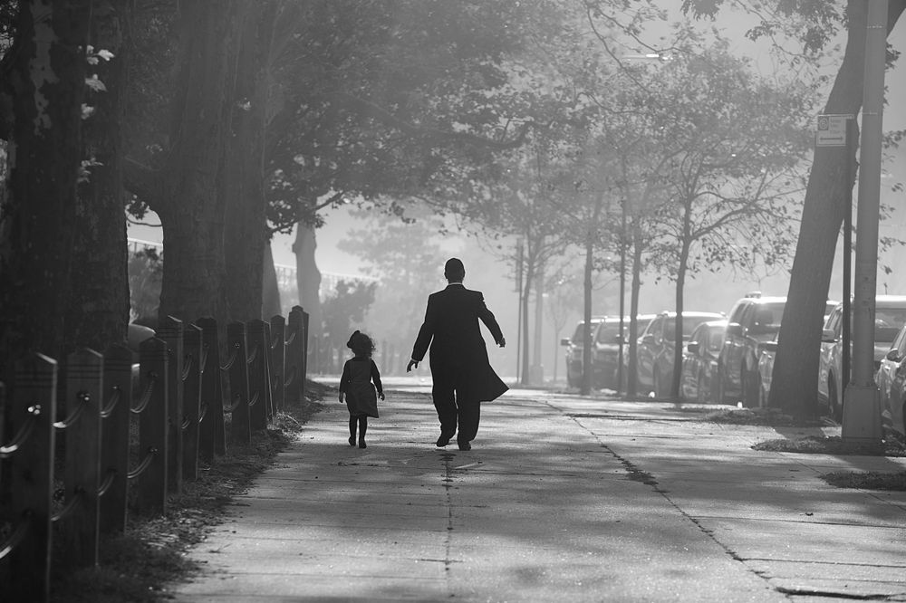 Cinematic black and white street photograph with figures walking through fog