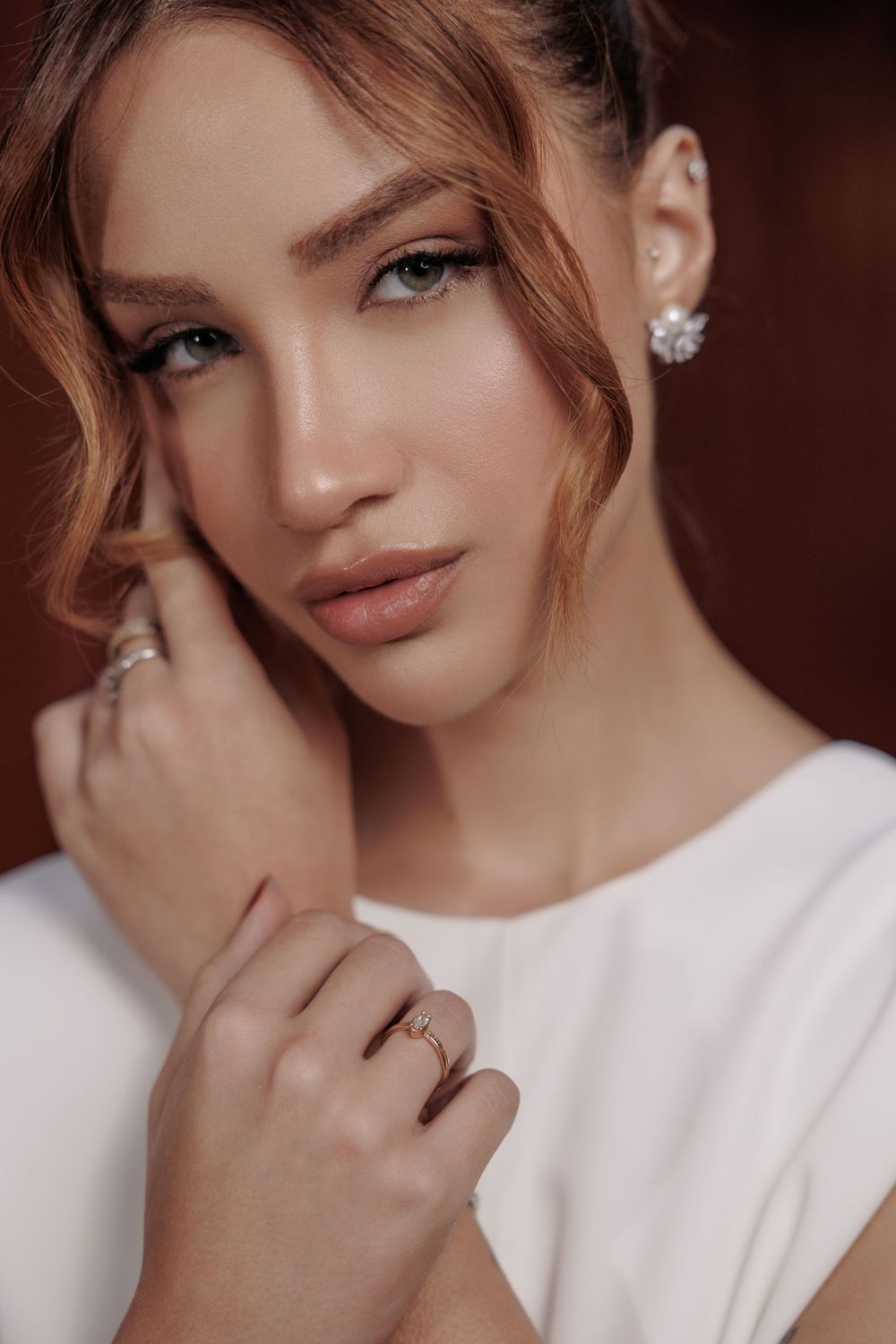 Portrait shot showcasing elegant jewelry and natural makeup with a dreamy warm-toned aesthetic.