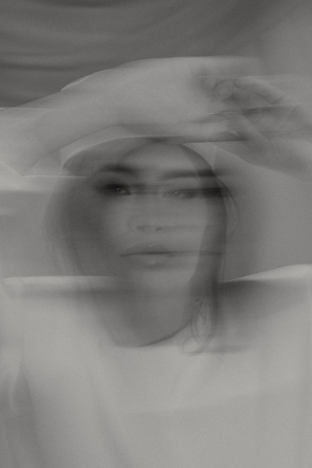 A blurred black and white photo sequence shows overlapping artistic portraits in a dreamlike motion effect.